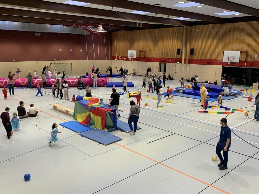 Ein großes Hallensportzentrum mit vielen Menschen, die aktiv an verschiedenen Stationen spielen.