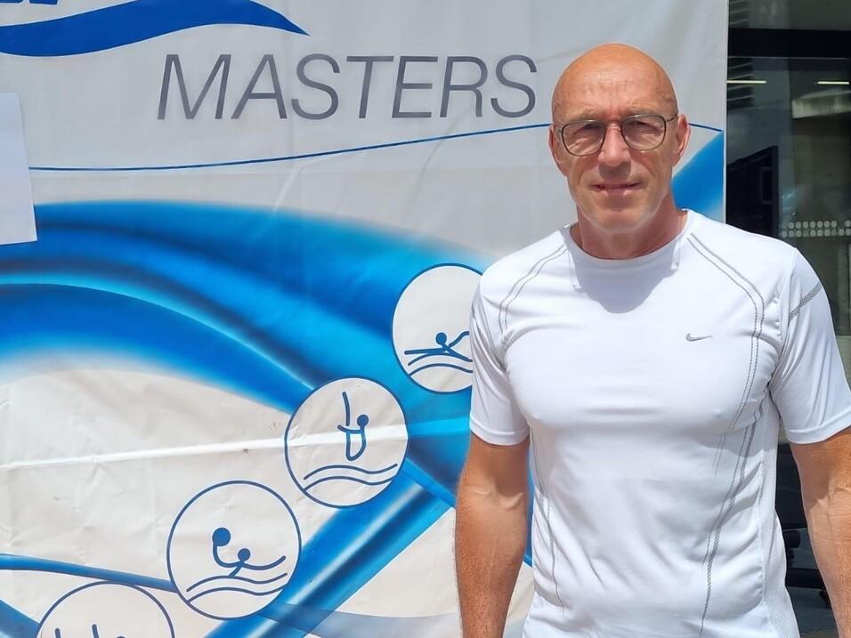 Mann in sportlicher Bekleidung steht vor einem Banner der DSV Masters mit dem Logo der DMM Dresden 2025.