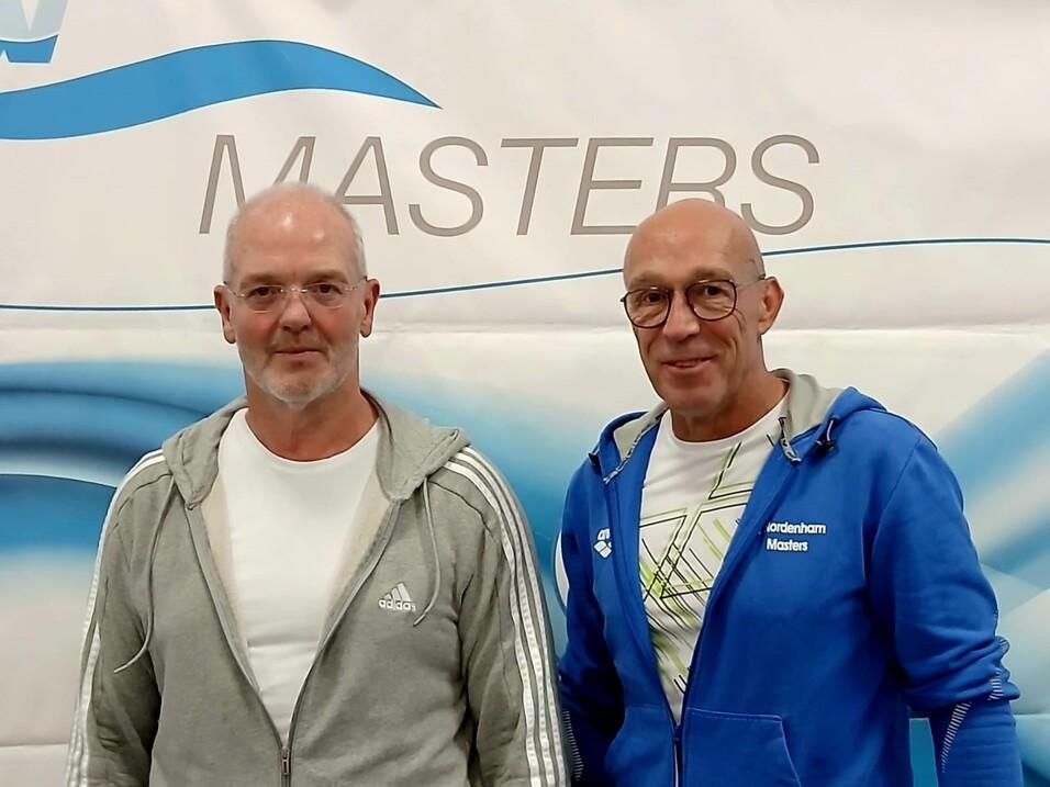 Zwei Männer stehen nebeneinander vor einem Banner der Masters.
