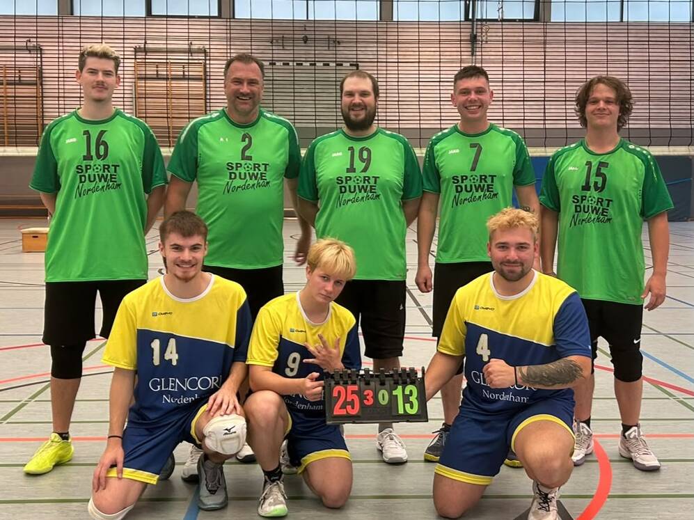 Fünf Männer in grünen Trikots und drei Männer in gelb-blauen Trikots posieren in einer Sporthalle, zwei knien und halten eine Anzeigetafel mit der Zahl '25:13'.