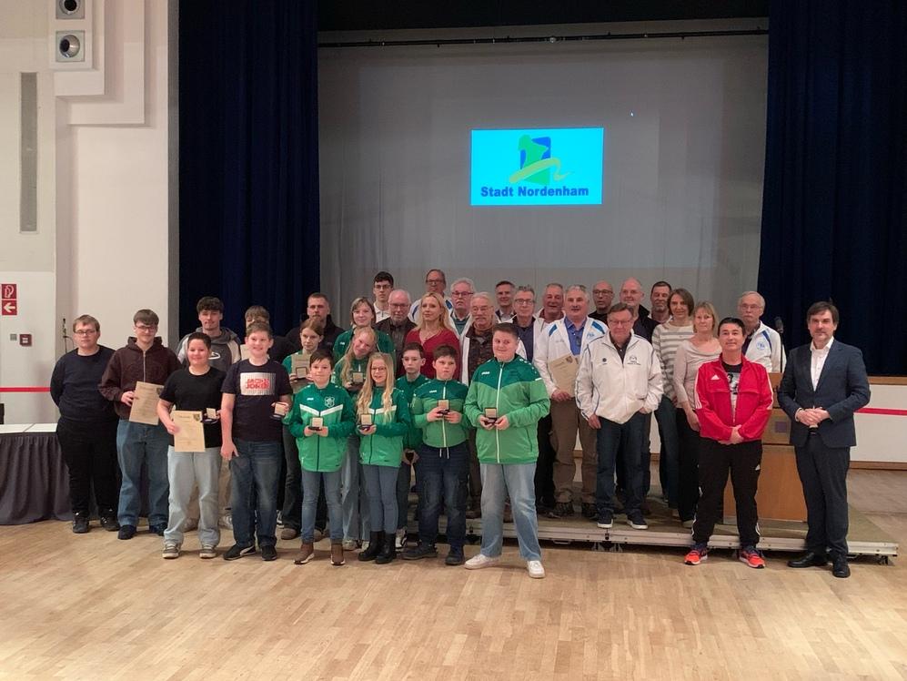 Sportler:innen posieren vor der Bühne während der Sportlerehrung in der Stadthalle Friedeburg.