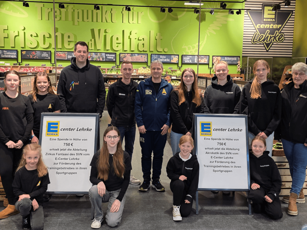 Übergabe von zwei Schecks für die Nachwuchsarbeit im Sportverein. Kinder und Erwachsene auf dem Bild vor einem grünen Hintergrund.